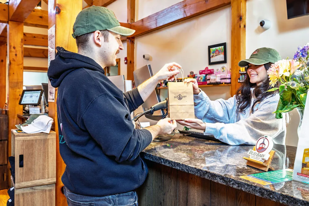 A Bud Barn team member hands a customer their order at the counter